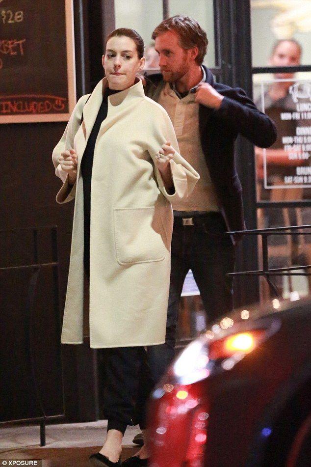 Pregnant Anne Hathaway wraps her growing bump under a chic cream coat