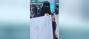 Two Muslim Women In Full Burqas Hold a Sign Saying 'Try On A Hijab'